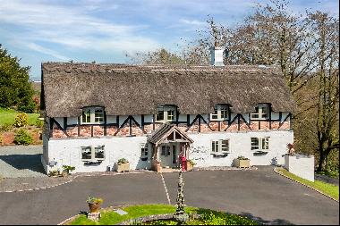 A delightful 3 bedroom oak framed thatched cottage with extensive gardens, with a total pl