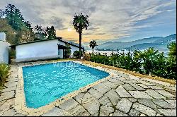 Charming small villa with a pool in Montagnola for sale, offering a spacious view of the 