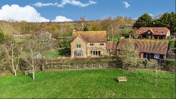 A beautiful Cotswold stone home in mature gardens overlooking the adjoining village green 