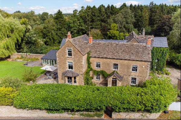 A six bedroom Grade II listed Cotswold stone family house with a walled garden, paddocks a