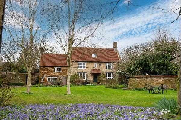 A lovely listed stone-built village house and barns with a south-facing garden are part of