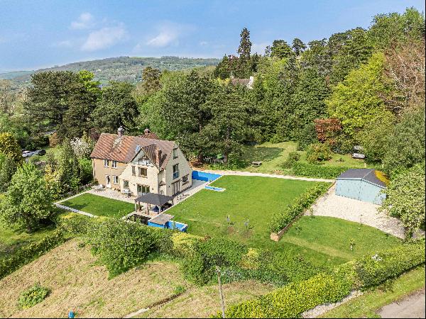 Set under the stunning wooded backdrop of Cleeve Hill, in mature gardens of 1.3 acres, a s
