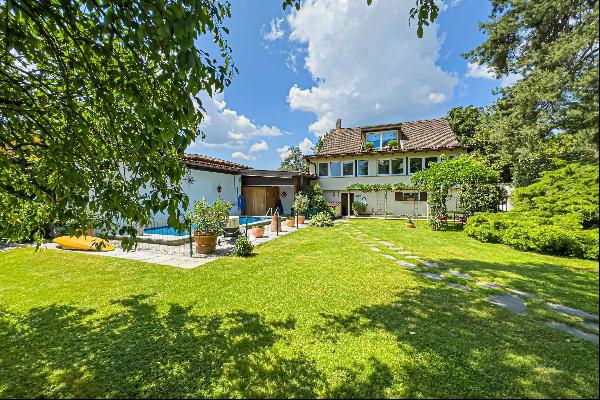 villa nestled in lush greenery featuring a swimming pool and proximity to lake lugano