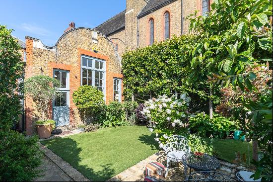 A detached converted school house with a beautiful garden and a gated driveway, located in