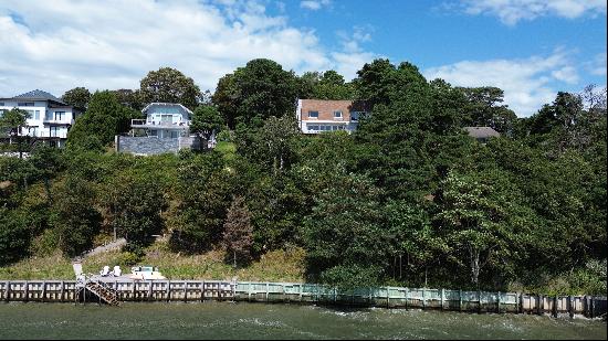 Nestled on a private road atop a bluff in Southampton, this modern waterfront home offers 