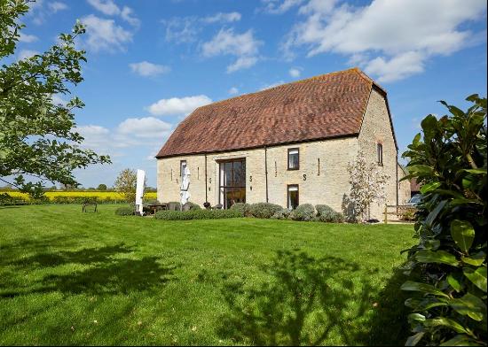 A five bedroom Grade II listed barn with gardens, paddock, and garage, set in approximatel