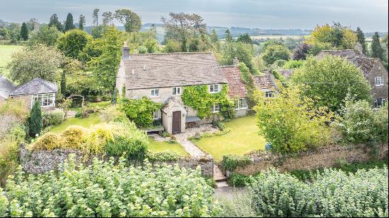 A charming double-fronted Cotswold stone village cottage with lovely walled gardens, and r